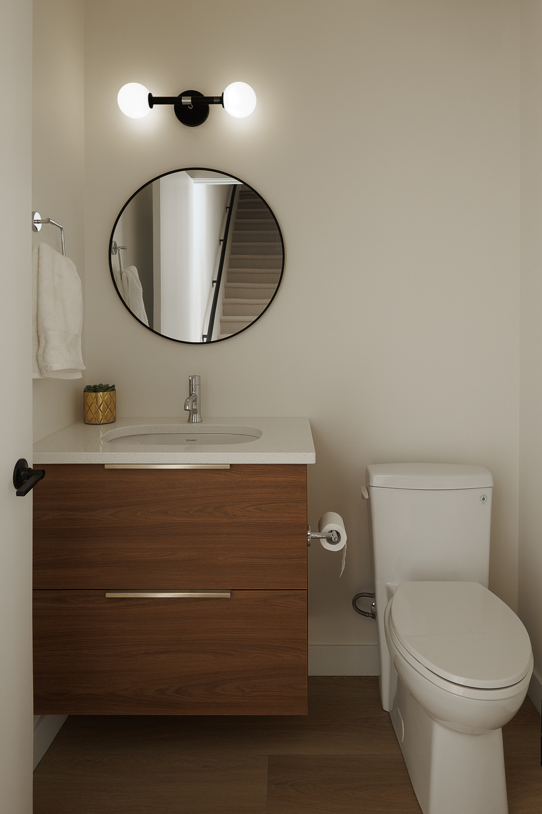 Powder room with walnut vanity and round mirror