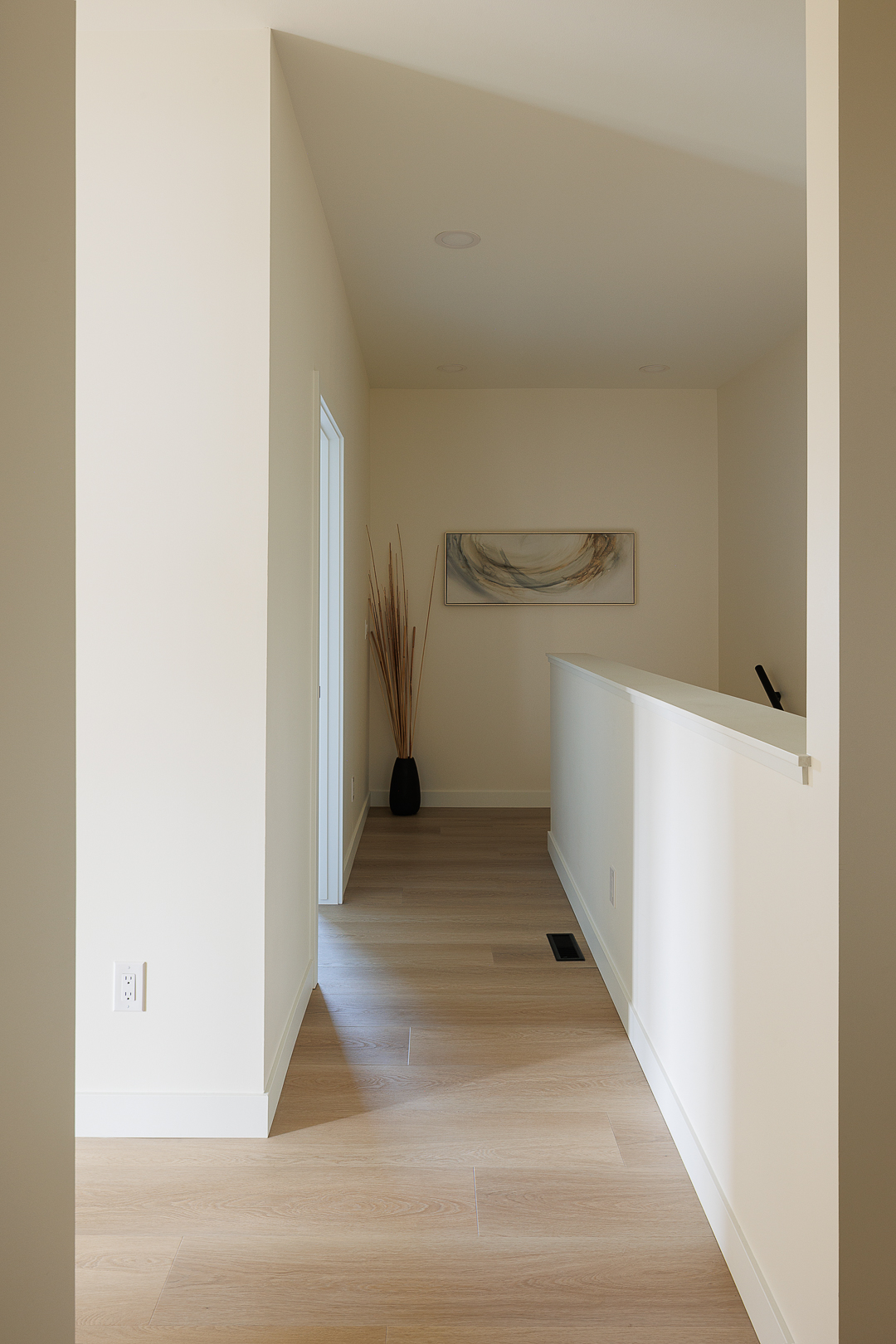 Hallway with oak flooring and framed artwork