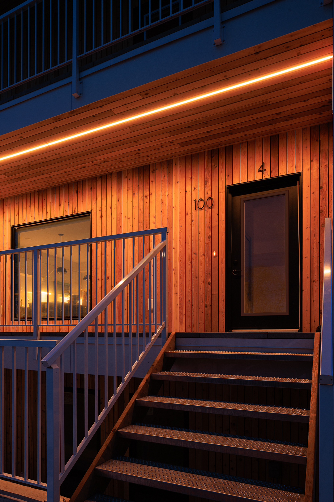 Front entry at dusk with unit 100 signage glowing
